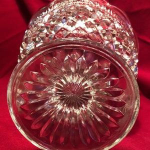 May include: A clear glass bowl with a diamond pattern on the sides and a flower-shaped pattern on the bottom.