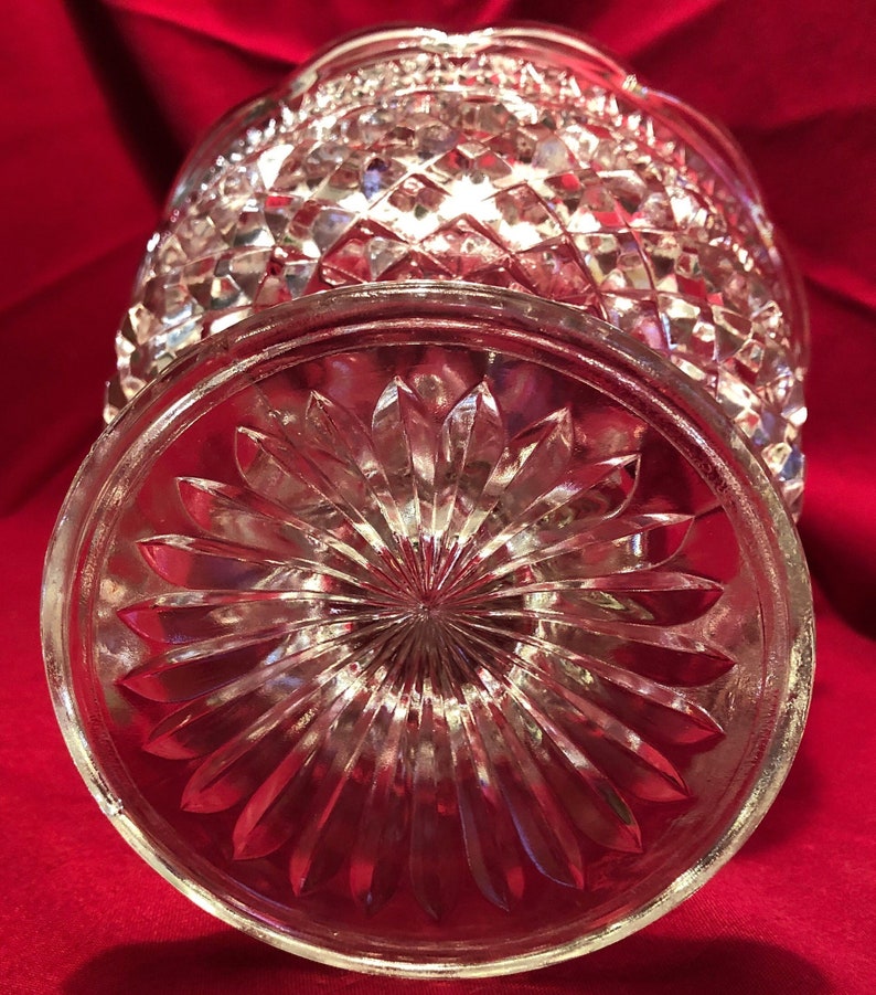 May include: A clear glass bowl with a diamond pattern on the sides and a flower-shaped pattern on the bottom.