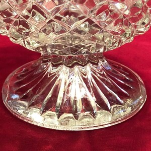 May include: A clear glass pedestal bowl with a diamond pattern on the top and a fluted base.