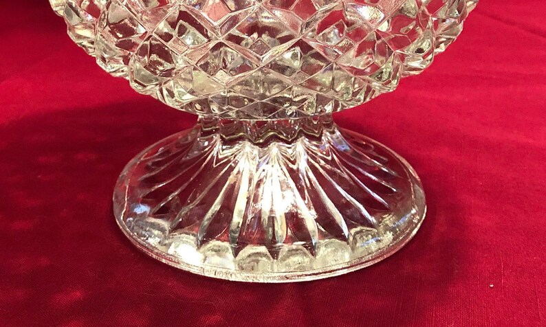 May include: A clear glass pedestal bowl with a diamond pattern on the top and a fluted base.