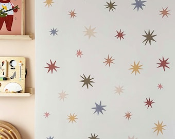 May include: A white wall adorned with numerous star-shaped decals in various colors, including brown, yellow, red, and blue. The stars vary in size and are scattered across the surface, creating a whimsical, celestial theme. The room has a playful, decorative aesthetic.