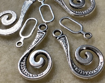May include: Silver-toned metal jewelry findings with a swirl design. The findings have a textured surface and a loop at the top for attaching to jewelry.