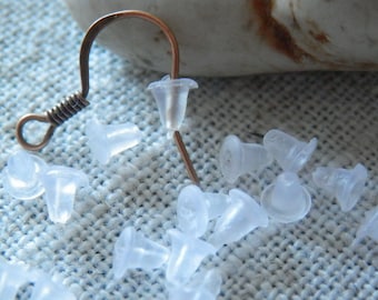 May include: A close-up of a pile of clear plastic earring backs. The backs are shaped like small cones and are designed to fit over the post of an earring.
