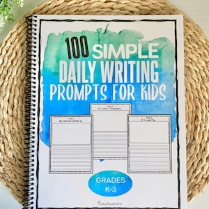 Może przedstawiać: Spiralnie oprawiony notatnik zatytułowany "100 Simple Daily Writing Prompts for Kids". Okładka ma akwarelowy wzór w odcieniach niebieskiego i zielonego. Zawiera podpowiedzi do pisania dla dzieci w klasach K-3.