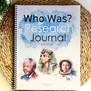 Może przedstawiać: Spiralnie oprawiony "Who Was? Research Journal" dla klas 3-8, z ilustracjami postaci historycznych. Okładka ma niebieski wz&oacute;r akwarelowy. Dziennik spoczywa na tkanej macie.