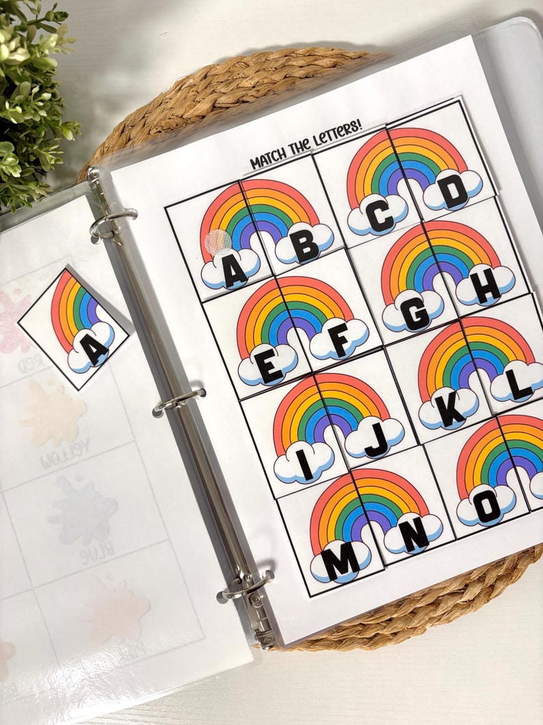 May include: A binder with educational printables. The pages feature colorful rainbow graphics with letters A through O. The text "MATCH THE LETTERS!" is at the top of the page. A rainbow sticker is also visible.