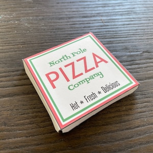 May include: A red and green pizza box with the text "North Pole Pizza Company" and "Hot * Fresh * Delicious" printed on it.