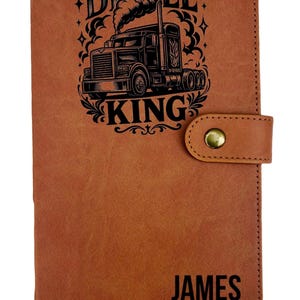 May include: A brown leather journal with the words "DIESEL KING" and a graphic of a semi-truck. The journal has a snap closure and a tassel. The name "JAMES" is printed on the bottom of the journal.