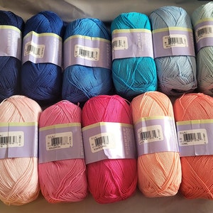 May include: A collection of colorful yarn skeins in various shades of blue, pink, coral, and green. Each skein is wrapped with a label. The yarn is likely made of alpaca wool, as indicated by the label.