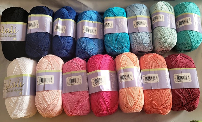 May include: A collection of colorful yarn skeins in various shades of blue, pink, coral, and green. Each skein is wrapped with a label. The yarn is likely made of alpaca wool, as indicated by the label.
