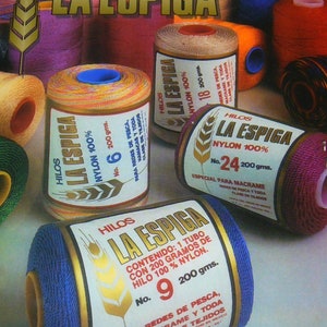 May include: Assortment of colorful spools of La Espiga nylon thread, each with a gold label and a different number. The labels feature the brand name, thread type, and weight. The spools are arranged on a white surface.