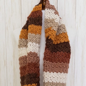 May include: A crocheted scarf with stripes of brown, beige, cream, and mustard yellow.