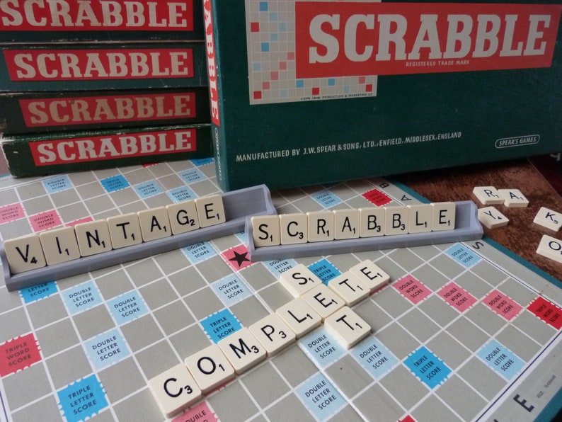 Puede incluir: Un tablero de juego de Scrabble vintage con fichas que deletrean las palabras "Vintage" y "Scrabble". El tablero de juego es verde y blanco con un patr&oacute;n rojo y blanco. Las fichas son blancas con letras negras.