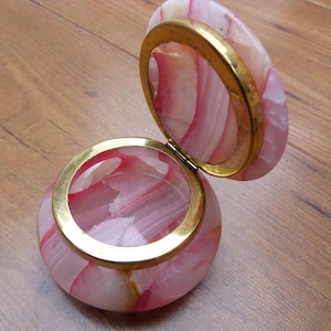 May include: A pink and white alabaster trinket box with a gold metal rim and hinge. The box is open and the inside is visible.