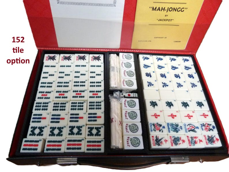 Peut inclure: Un jeu de Mah-Jongg de la marque Jackpot dans une mallette rouge. Le set comprend 152 tuiles avec divers symboles, caract&egrave;res et motifs floraux, ainsi que des b&acirc;tonnets de pari blancs et des d&eacute;s. Le couvercle int&eacute;rieur porte une &eacute;tiquette jaune.