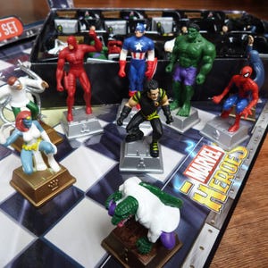 以下が含まれることがあります： デアデビル、キャプテン・アメリカ、ハルク、スパイダーマンなど、マーベル・ヒーローズのキャラクターが揃ったチェスセット。チェスの駒はプラスチック製で、明るい色で塗られています。チェス盤は白黒です。