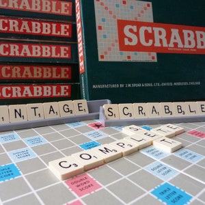 Puede incluir: Un tablero de juego de Scrabble vintage con fichas que deletrean las palabras "vintage" y "completo". El tablero de juego est&aacute; hecho de madera y tiene una superficie de fieltro verde. Las fichas son de pl&aacute;stico y tienen letras impresas en ellas. El juego est&aacute; fabricado por J.W. Spear & Sons, Ltd. Enfield, Middlesex, Inglaterra.