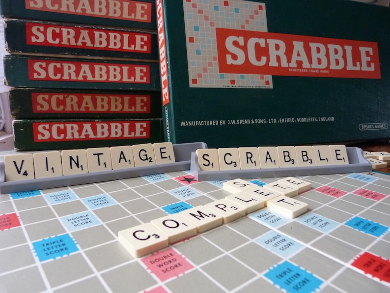 Puede incluir: Un tablero de juego de Scrabble vintage con fichas que deletrean las palabras "vintage" y "completo". El tablero de juego est&aacute; hecho de madera y tiene una superficie de fieltro verde. Las fichas son de pl&aacute;stico y tienen letras impresas en ellas. El juego est&aacute; fabricado por J.W. Spear & Sons, Ltd. Enfield, Middlesex, Inglaterra.