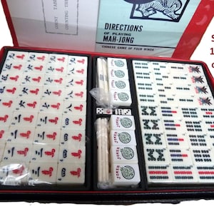 Peut inclure: Un jeu de Mah-Jong dans un coffret rouge et noir, comprenant des tuiles blanches avec des caract&egrave;res, symboles et marquages Joker en rouge, bleu et vert. Le set inclut un manuel intitul&eacute; Directions of Playing Mah-Jong et une option 152 tuiles.