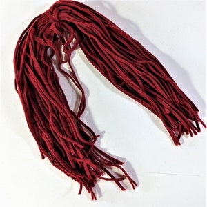 May include: A bundle of dark red shoelaces, arranged in a loose, flowing pattern against a white background. The laces are thick and appear to be made of a durable material. The overall presentation suggests a focus on footwear accessories.