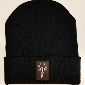 May include: Black beanie with a brown leather patch featuring a white phoenix design.
