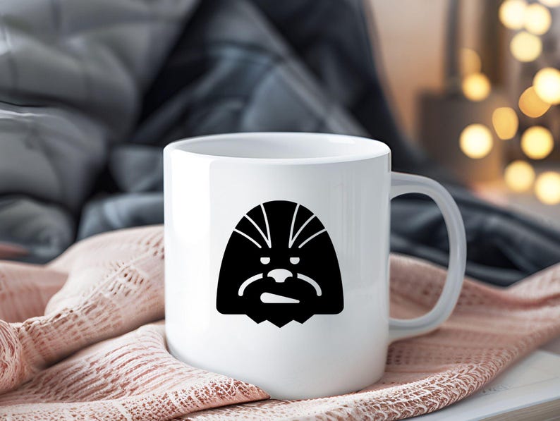 May include: A white ceramic mug featuring a black graphic illustration of a stylized Wookiee character face on the front. The mug has a smooth, glossy finish with a standard handle on the right side and a simple, cylindrical shape for holding beverages.