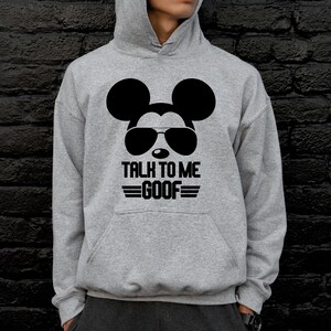 May include: A heather gray hooded sweatshirt featuring a black graphic of a mouse silhouette wearing sunglasses. Below the graphic, the text reads TALK TO ME GOOF in a bold, black sans-serif font, accented by horizontal lines above and below.