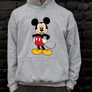 Pu&ograve; includere: Una felpa con cappuccio grigio melange caratterizzata da una grafica centrale di Topolino. Il personaggio &egrave; raffigurato con orecchie nere, viso color carne, pantaloncini rossi con due bottoni bianchi, guanti bianchi e grandi scarpe gialle.