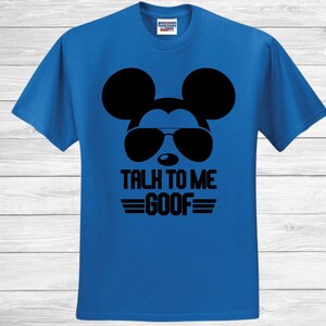 May include: A bright blue short-sleeved t-shirt featuring a black graphic of a mouse silhouette wearing sunglasses. Below the graphic, the text reads "TALK TO ME GOOF" in bold black capital letters, flanked by two horizontal black lines on each side.