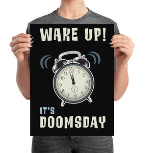 May include: Black poster with the text "WAKE UP! IT'S DOOMSDAY" in white. A vintage alarm clock graphic is in the center. The clock hands point to 10:59. The poster is held by a person.