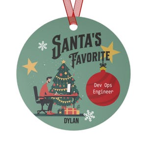 May include: Round Christmas ornament with a red ribbon. The ornament features a green background with the text "Santa's Favorite" and a graphic of a person at a desk with a Christmas tree. The text "Dev Ops Engineer" is on a red ornament.