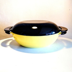 May include: A yellow and black enamel cast iron casserole dish with two handles. The dish is round and has a lid.