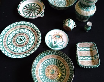 May include: A collection of ceramic dishes and vases with green and brown geometric patterns. The dishes are various sizes and shapes, including a round plate, a square dish, and a small bowl. The vases are tall and slender, with a floral design.