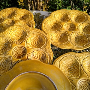 Könnte beinhalten: Set aus vier gelben Keramik-Austerntellern mit einem erhabenen Design. Die Teller wurden von Boom Frères in Belgien hergestellt.