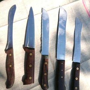May include: Six kitchen knives with wooden handles. The knives have different blade shapes and sizes. The blades are made of stainless steel.