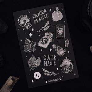 Op de afbeelding: Een zwarte kaart met witte illustraties van verschillende magische voorwerpen, waaronder een kristal, een ketel, een fles, een boek en een kaars. De tekst "Queer Magic" staat twee keer op de kaart.