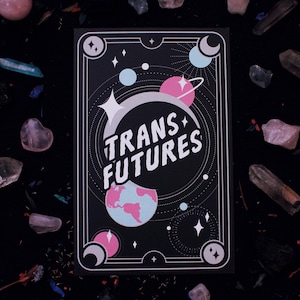 May include: A black card with a white border and a pink, blue, and white illustration of planets and stars. The text "TRANS+ FUTURES" is written in white letters on a black circle.