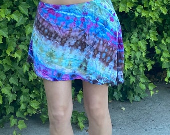 May include: A tie-dye mini skirt with a blue, green, pink, and brown color scheme. The skirt is made of a soft, flowing fabric.