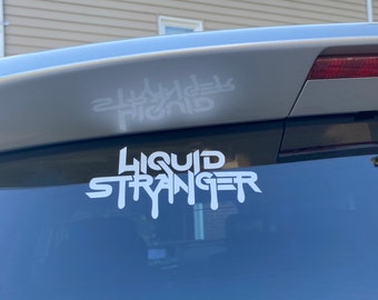 May include: White "LIQUID STRANGER" sticker with dripping font on a car window. Above, a smaller white sticker reads "HYBRID" in a mirrored, stylized font. The stickers are applied to a silver car, with a house visible in the background.