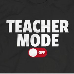 Puede incluir: Una camiseta negra con texto blanco que dice "Modo Profesor" y un interruptor de palanca rojo con la palabra "OFF" en él.
