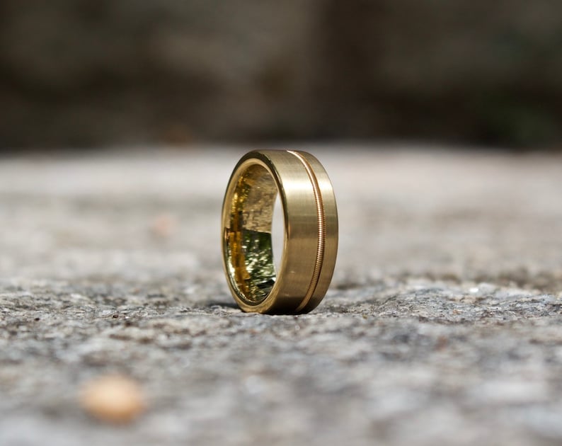 Puede incluir: Una banda de boda de oro con un borde biselado y un acabado pulido.