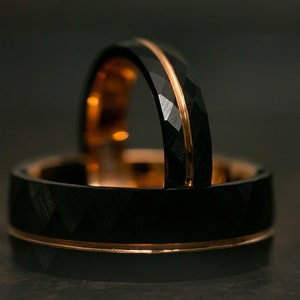 Puede incluir: Dos anillos de carburo de tungsteno negro con una incrustaci&oacute;n de oro rosa. Los anillos tienen un borde biselado y un acabado cepillado.