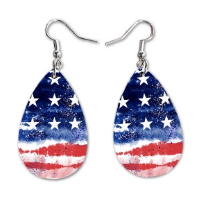 May include: A pair of teardrop-shaped earrings with a watercolor-style American flag design. The earrings have silver hooks.