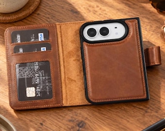 May include: A brown leather wallet phone case featuring a dedicated compartment for a smartphone with a dual-lens camera cutout. The interior includes three card slots, one with a clear window, and a secure side tab closure mechanism.