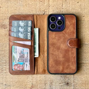 Puede incluir: Una funda de tel&eacute;fono de cuero marr&oacute;n con una secci&oacute;n de billetera. La billetera contiene tarjetas de cr&eacute;dito, una licencia de conducir y efectivo. La funda del tel&eacute;fono est&aacute; abierta, revelando el tel&eacute;fono y la secci&oacute;n de la billetera. La funda del tel&eacute;fono tiene un cierre magn&eacute;tico.