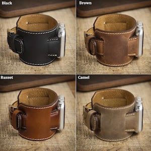 Peut inclure: Une collection de quatre bracelets de montre larges en cuir pour montre connect&eacute;e, pr&eacute;sent&eacute;s en noir, marron, roux et camel. Chaque bracelet pr&eacute;sente un design &agrave; manchette &eacute;paisse, des coutures contrast&eacute;es claires, une boucle et un connecteur argent&eacute;.