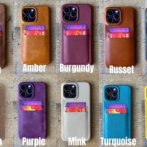 Peut inclure: Dix &eacute;tuis de smartphone en cuir avec porte-cartes, chacun contenant une carte aux graphismes violets et rouges. Les couleurs incluent marron, ambre, bordeaux, roux, noir, moka, violet, vison, turquoise et jaune. Chaque &eacute;tui a une d&eacute;coupe cam&eacute;ra.