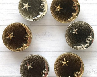 May include: Six gold and silver crescent moon buttons with a star design. The buttons have a textured surface and are perfect for adding a touch of whimsy to any project.