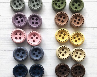 May include: Assortment of 18 wooden buttons in various colors, including blue, green, brown, yellow, pink, and purple. Each button has four holes and a decorative stitched edge.