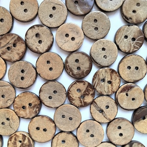 May include: A collection of brown coconut shell buttons with two holes each. The buttons are arranged in a random pattern on a white background.